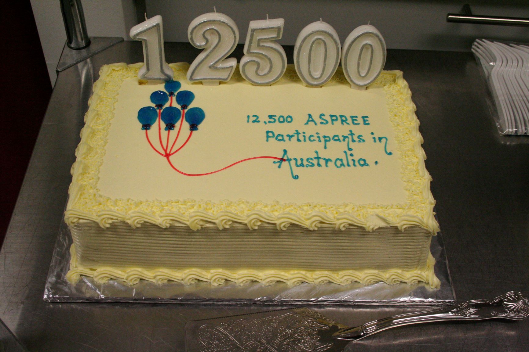 Yellow cake with 12,500 ASPREE participants in Australia written in blue icing