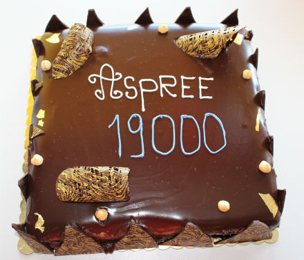 A chocolate cake with ASPREE 19000 written in blue and white icing on top.