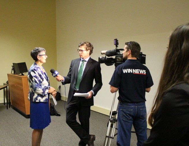 A woman is interviewed by a TV news crew