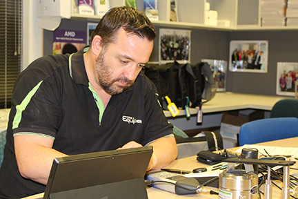A bearded caucasian man in a black and green shirts is observing measures on devices.