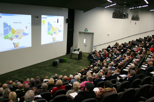 Inside a large lecture theatre, with a map of ASPREE sites projected onto the wall