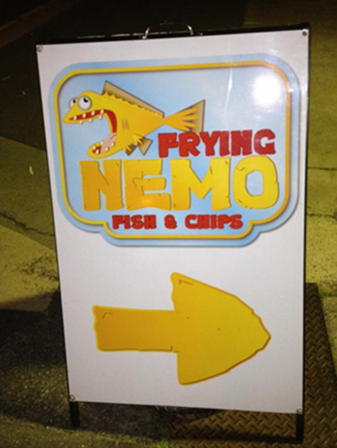 An A frame board with writing that says Frying Nemo fish and chips printed in yellow and red